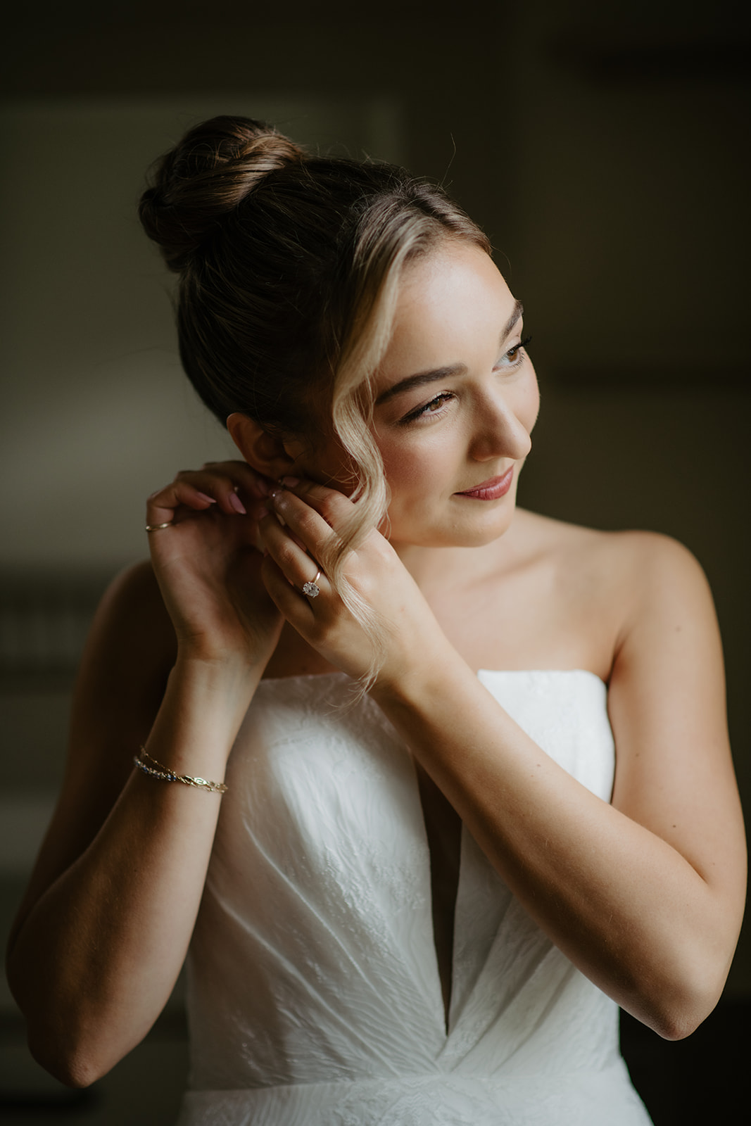 Close-up portrait of the bride putting on her earrings.