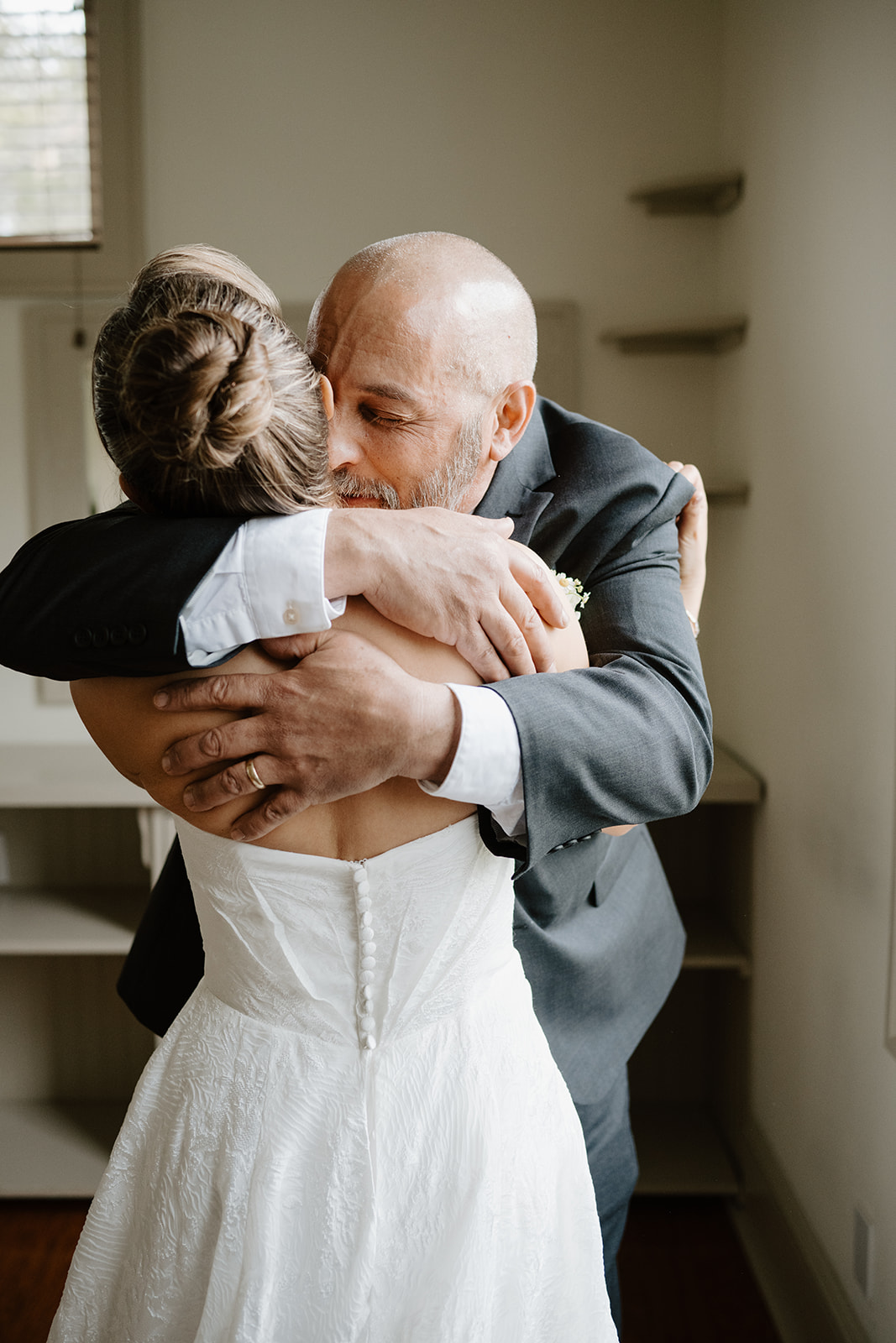 Close-up color photo of the father and daughter hugging tightly, both with emotional expressions.