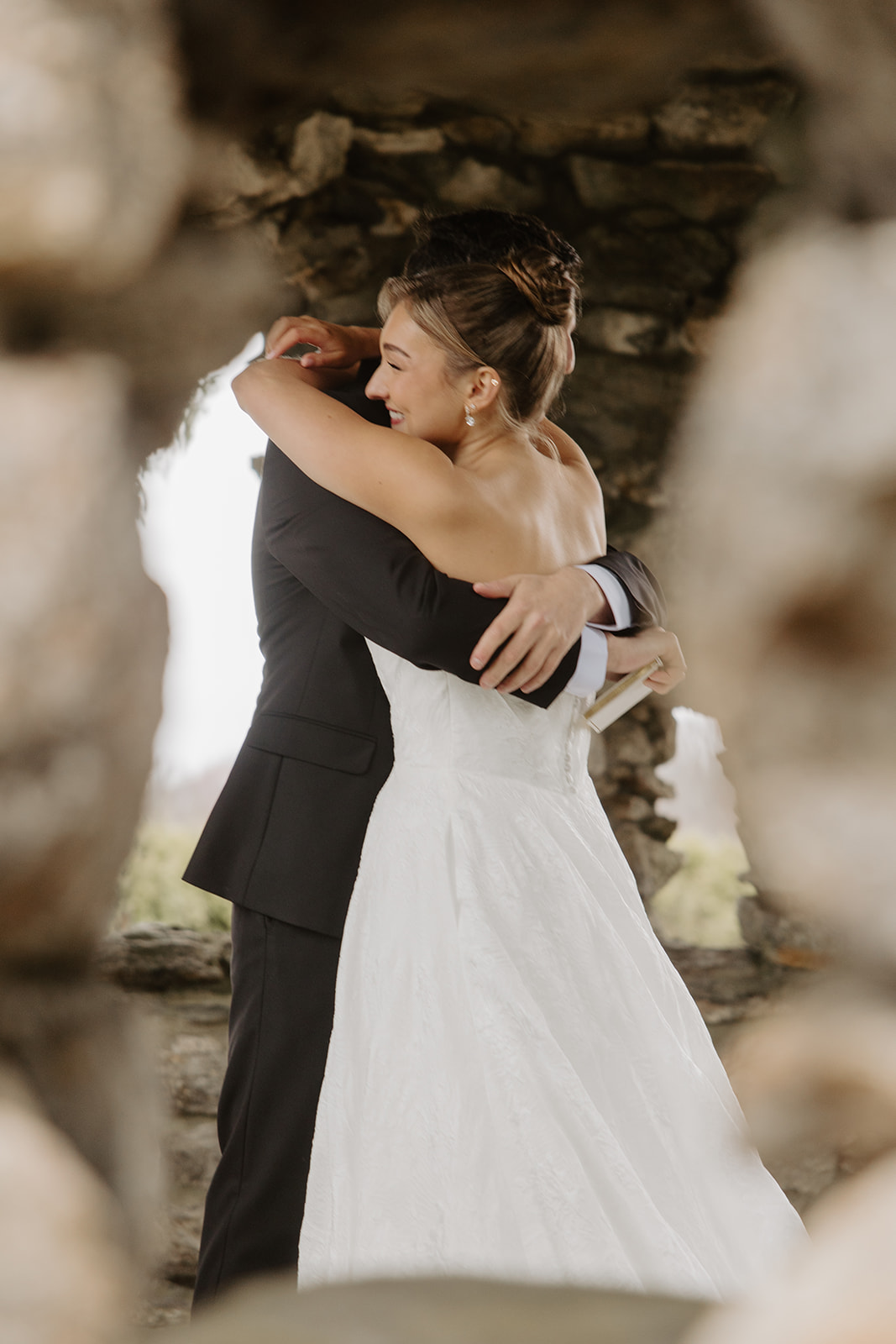 Couple sharing a warm hug inside the archway of the stone gazebo.