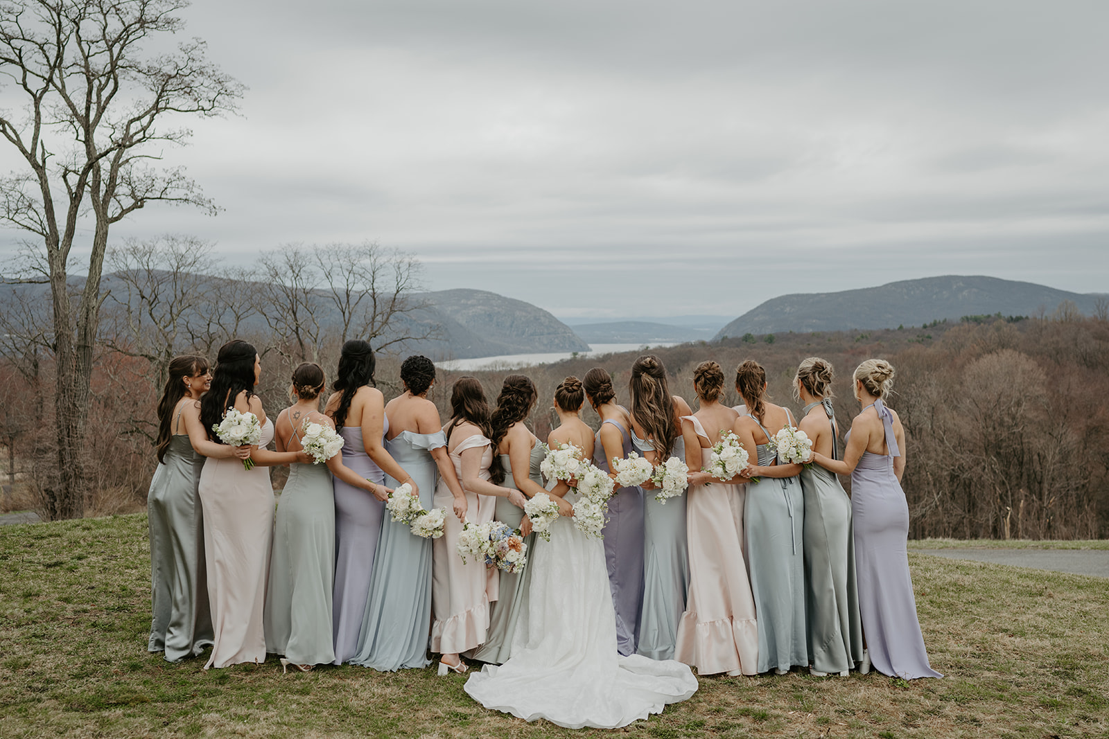 Bride and bridesmaids looking at the mountain view, backs to the camera, holding their bouquets.