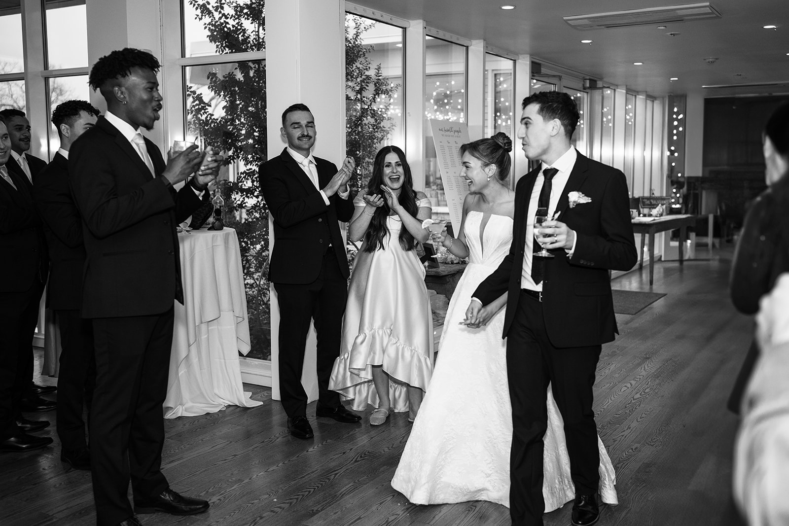 Black and white photo of the couple's grand entrance into the reception ballroom, guests applauding.