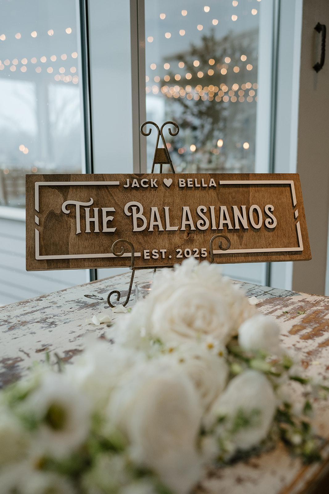 Custom wooden table sign reading 'Jack ♥ Bella - THE BALASIANOS - EST. 2025'.