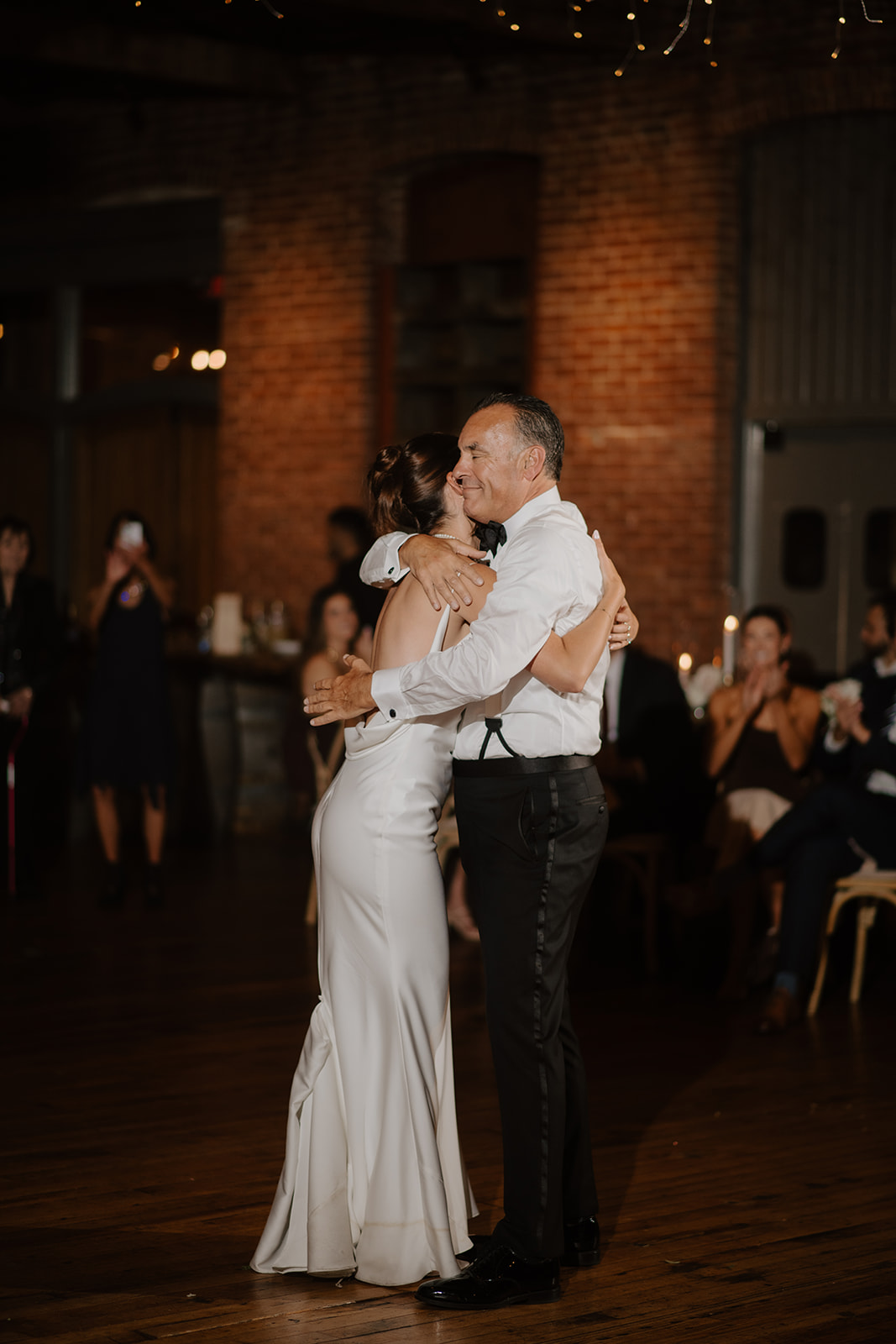 Bride hugs her father tightly during their dance on the reception floor.