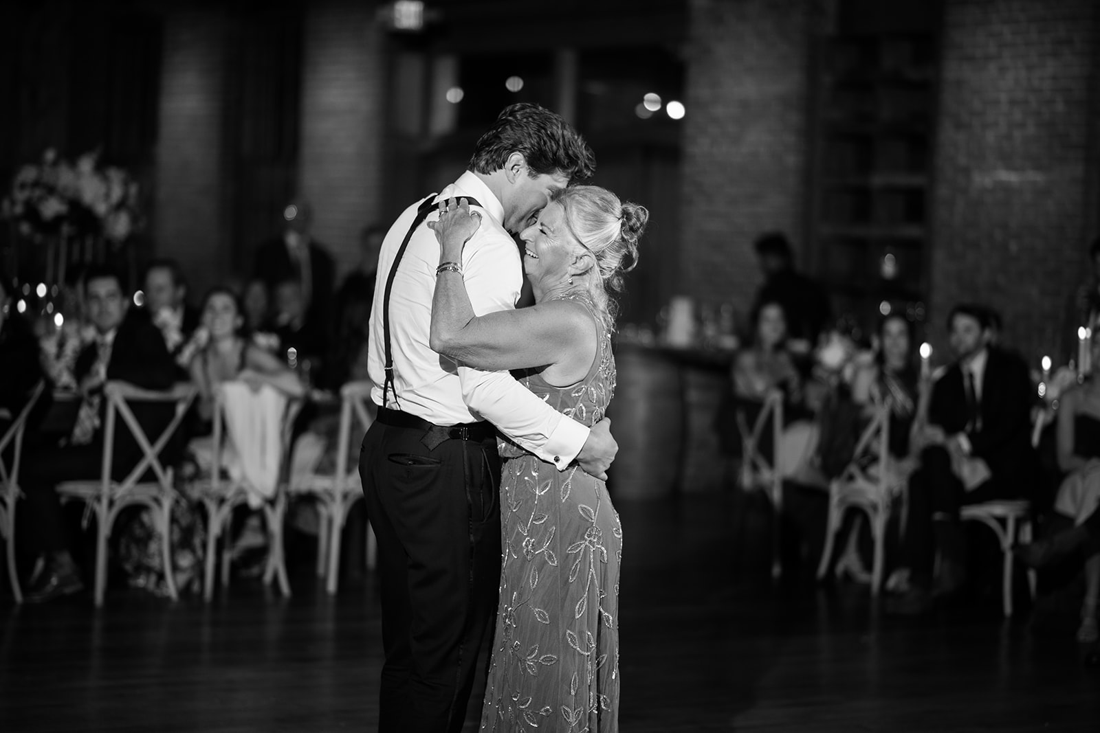 Black and white photo of the groom hugging his mother warmly during their dance at the reception.