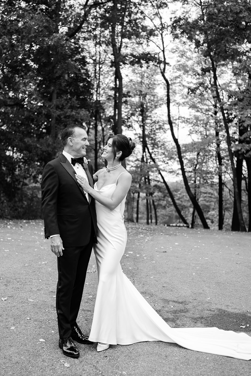 Black and white photo of the bride smiling lovingly at her father during their outdoor portrait session.