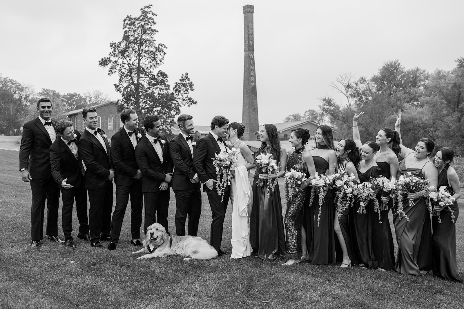 Black and white photo of the wedding party smiling on the lawn with their dog at City Winery.