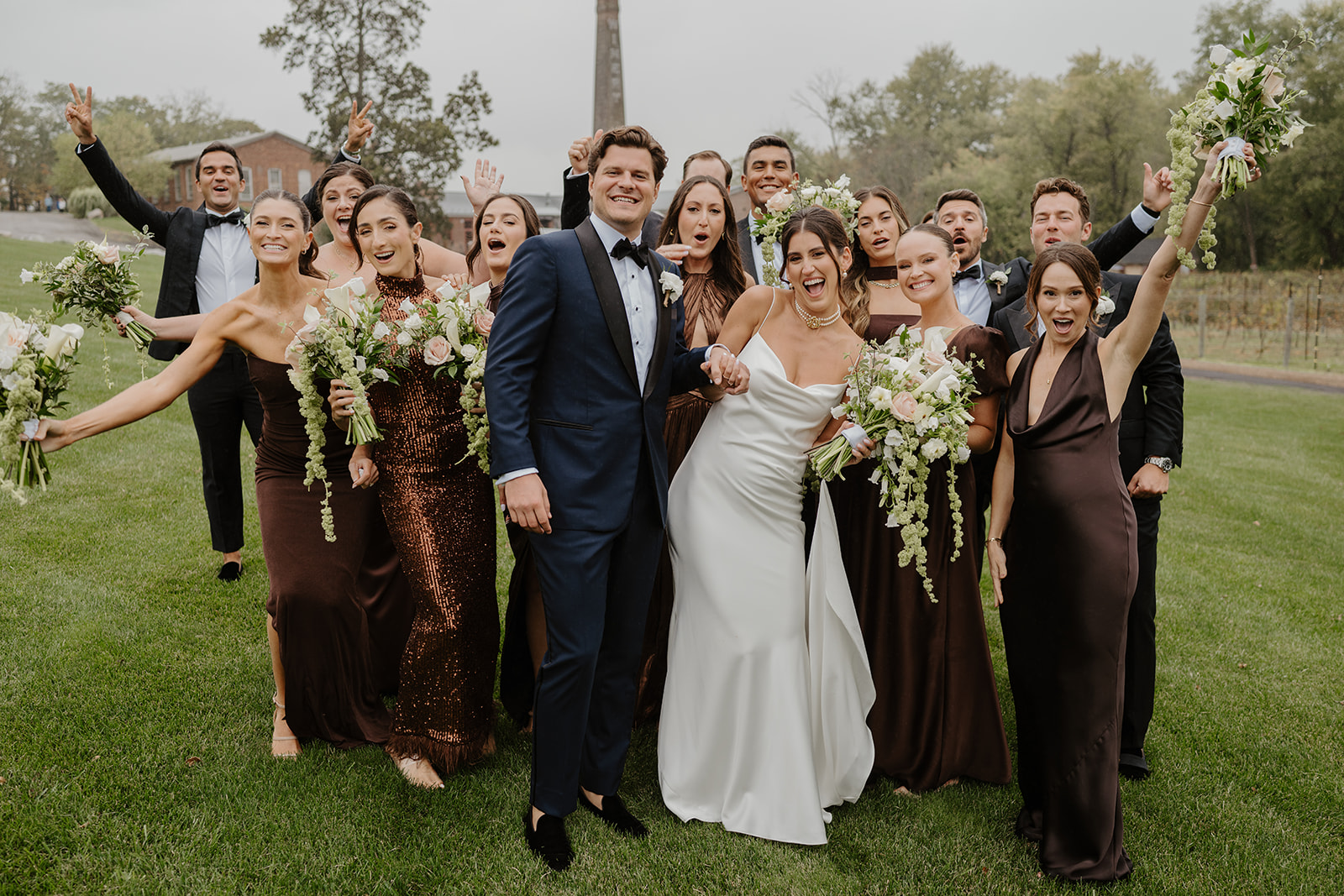 Wedding party poses for a fun, animated group photo on the lawn at City Winery.