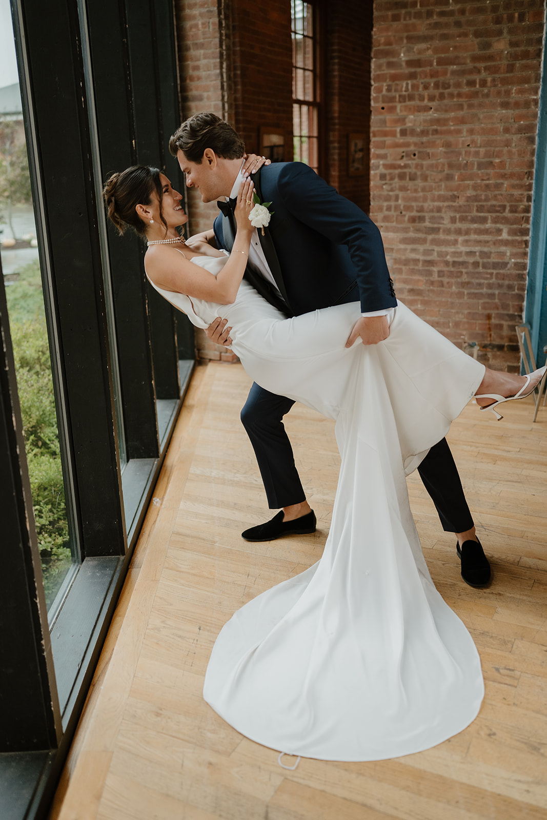 Groom dips the bride on the wooden floor of City Winery as they share a joyful smile.