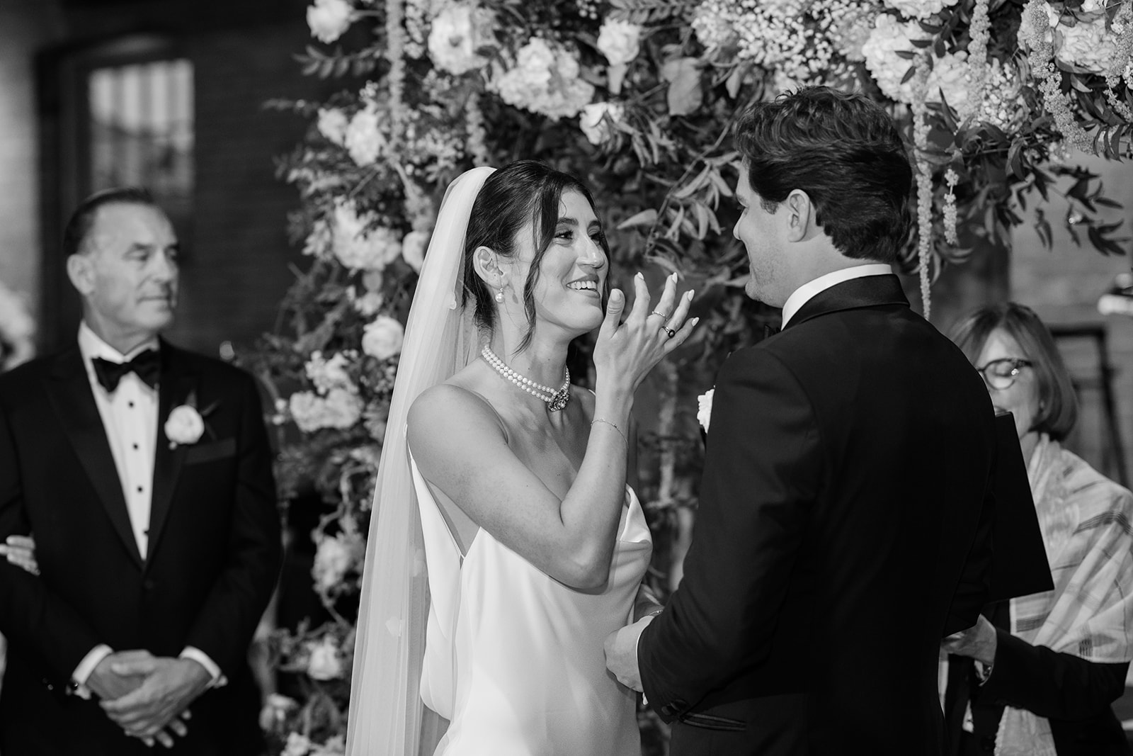 Black and white photo of the bride wiping a happy tear during ceremony vows.