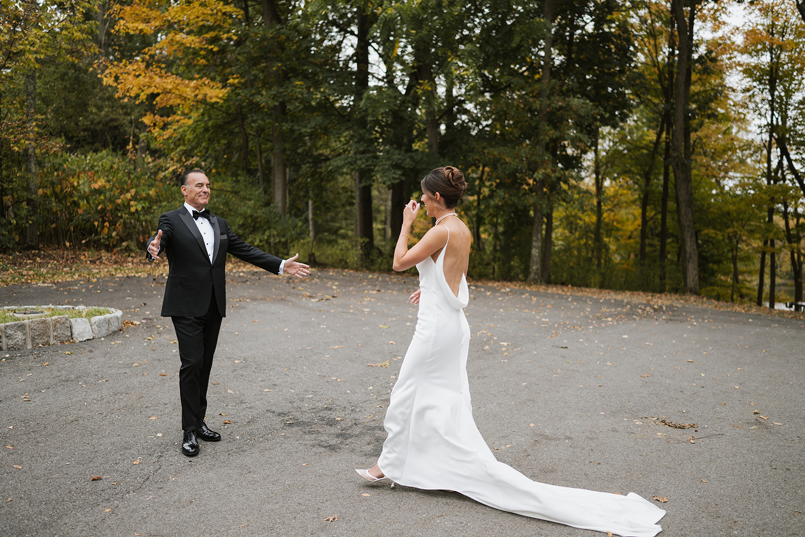 Father of the bride opens his arms with a joyful smile for a first look with his daughter.