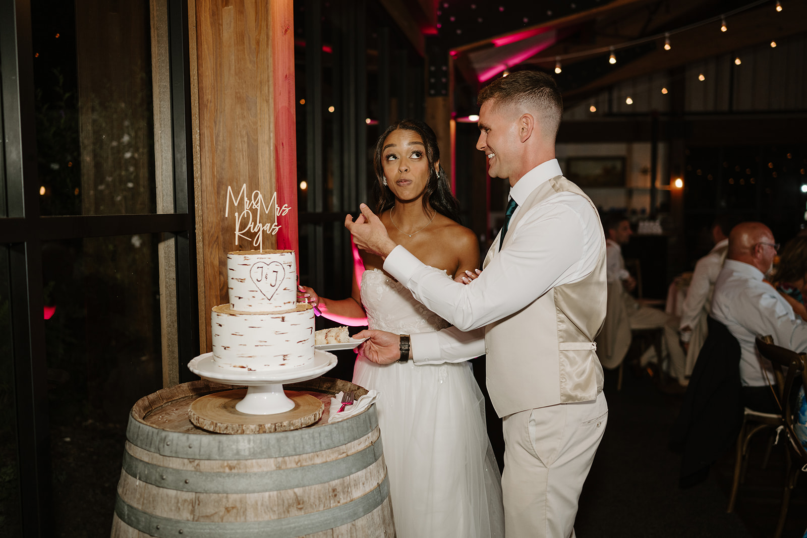 Bride and groom cut their wedding cake displayed on a wine barrel.