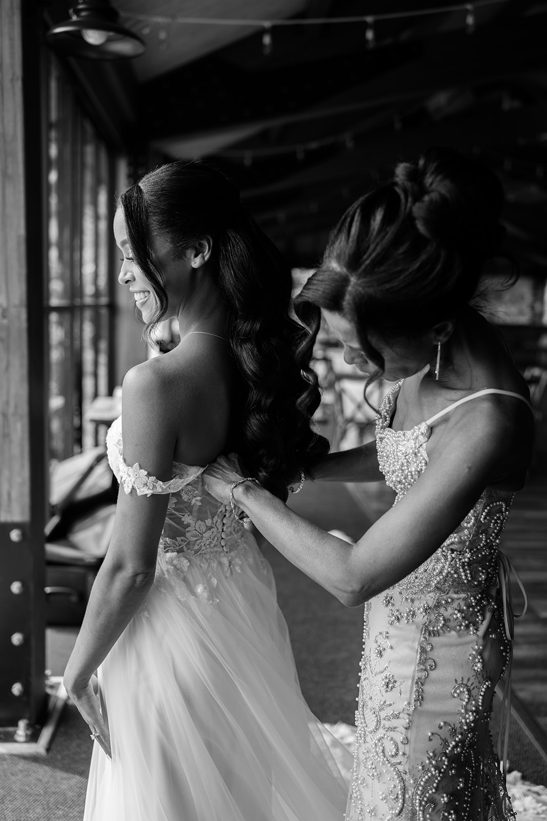 Bride shares a quiet laugh with a bridesmaid in a beaded gown before the ceremony.
