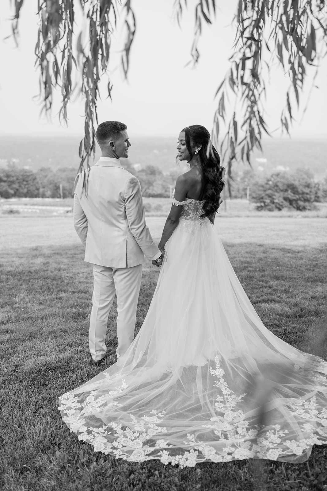 Black and white photo of the couple holding hands, looking out over the valley.