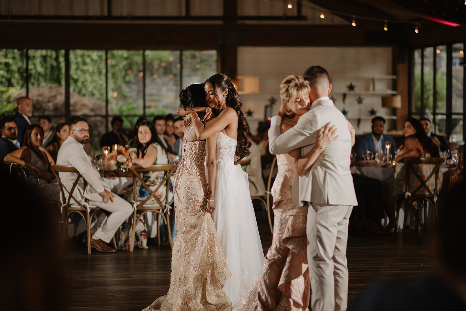 Bride and groom hold each other during their first dance among the reception tables.