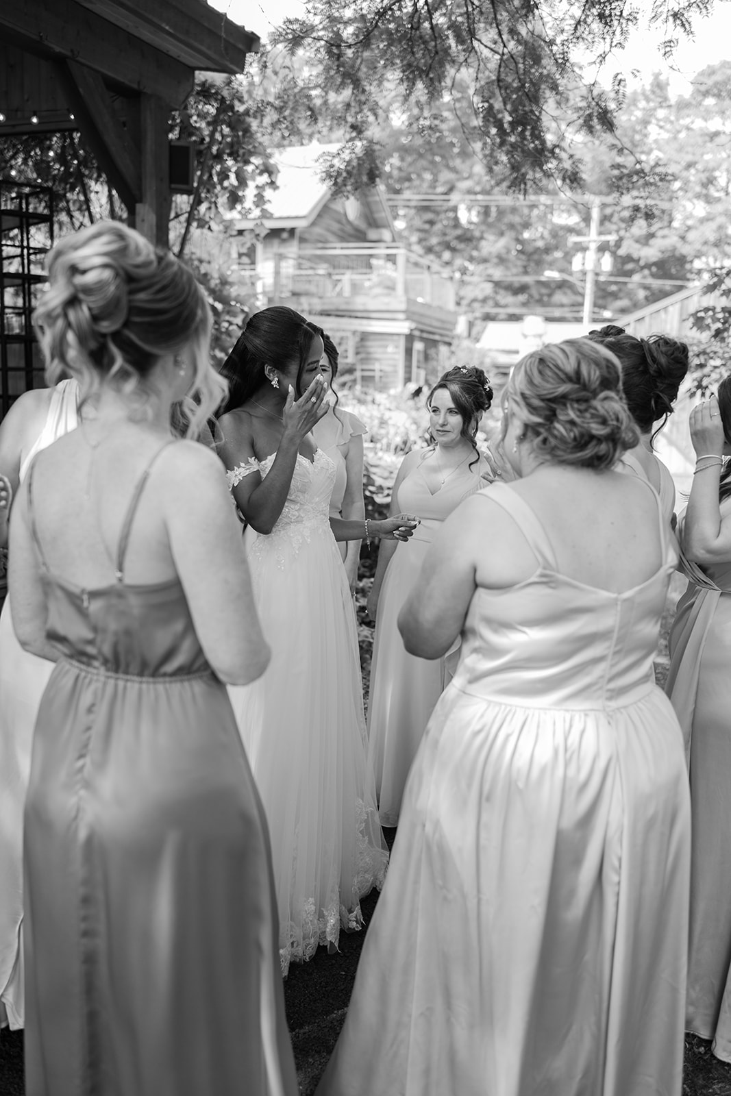 Black and white photo of the bridal party sharing an emotional moment outdoors.