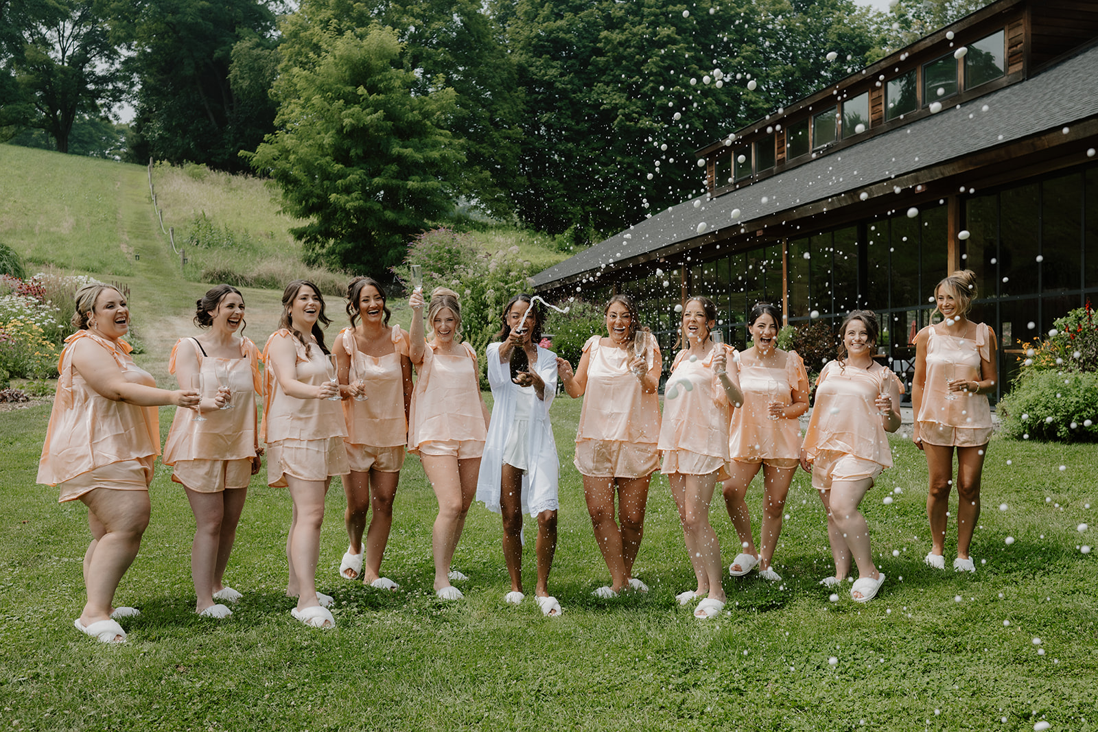Bride and her bridesmaids walk together in matching pajamas across the lawn.