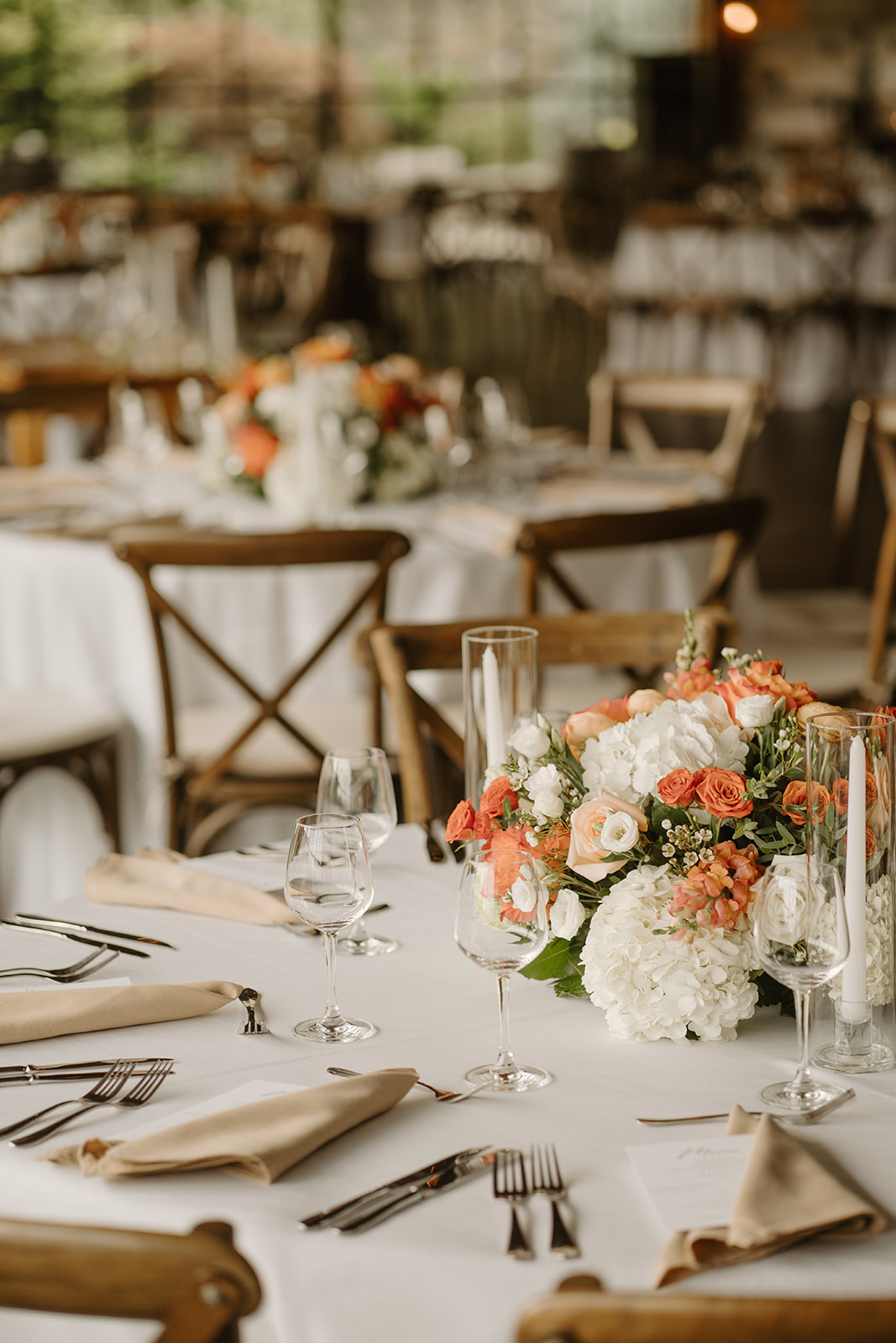 Long reception tables dressed with orange and white florals and tapered candles.