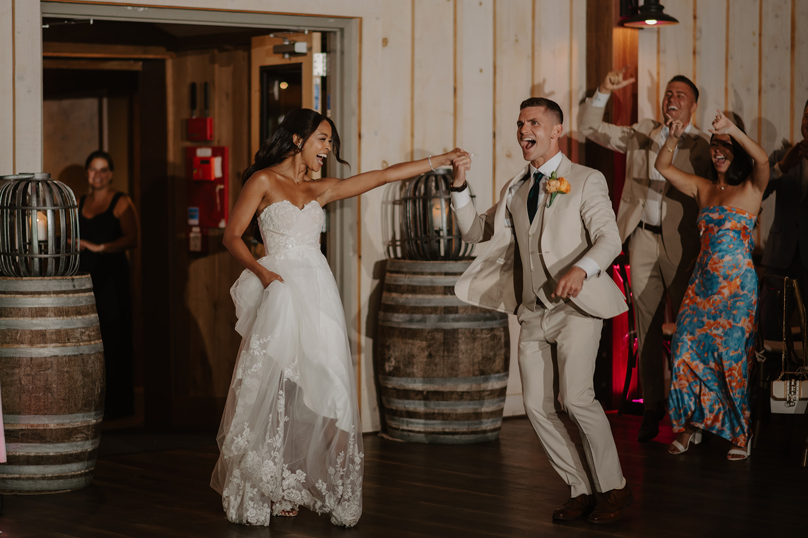 Bride and groom dance into their reception as guests cheer them on.