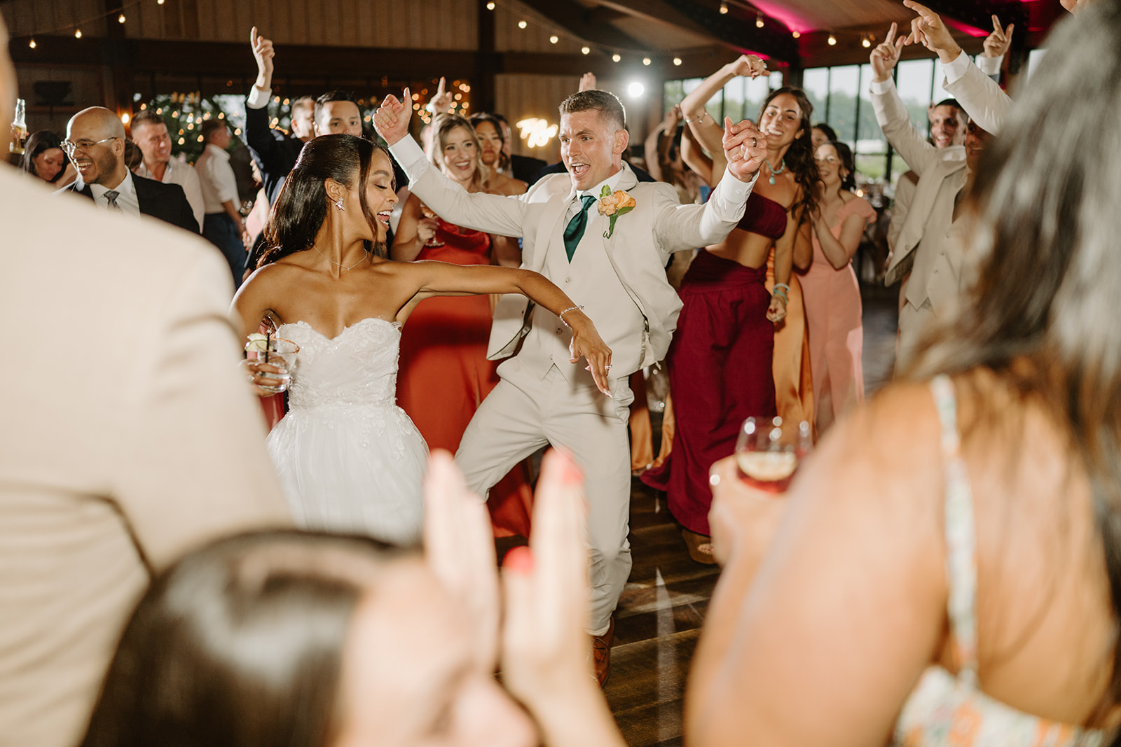 Guests raise their arms around the bride and groom during the reception party.