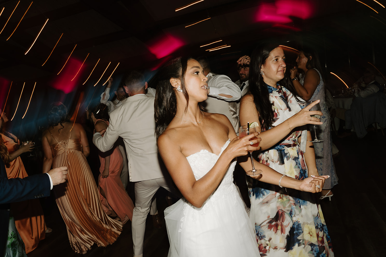 Bride dances with guests under the glow of the reception lights.