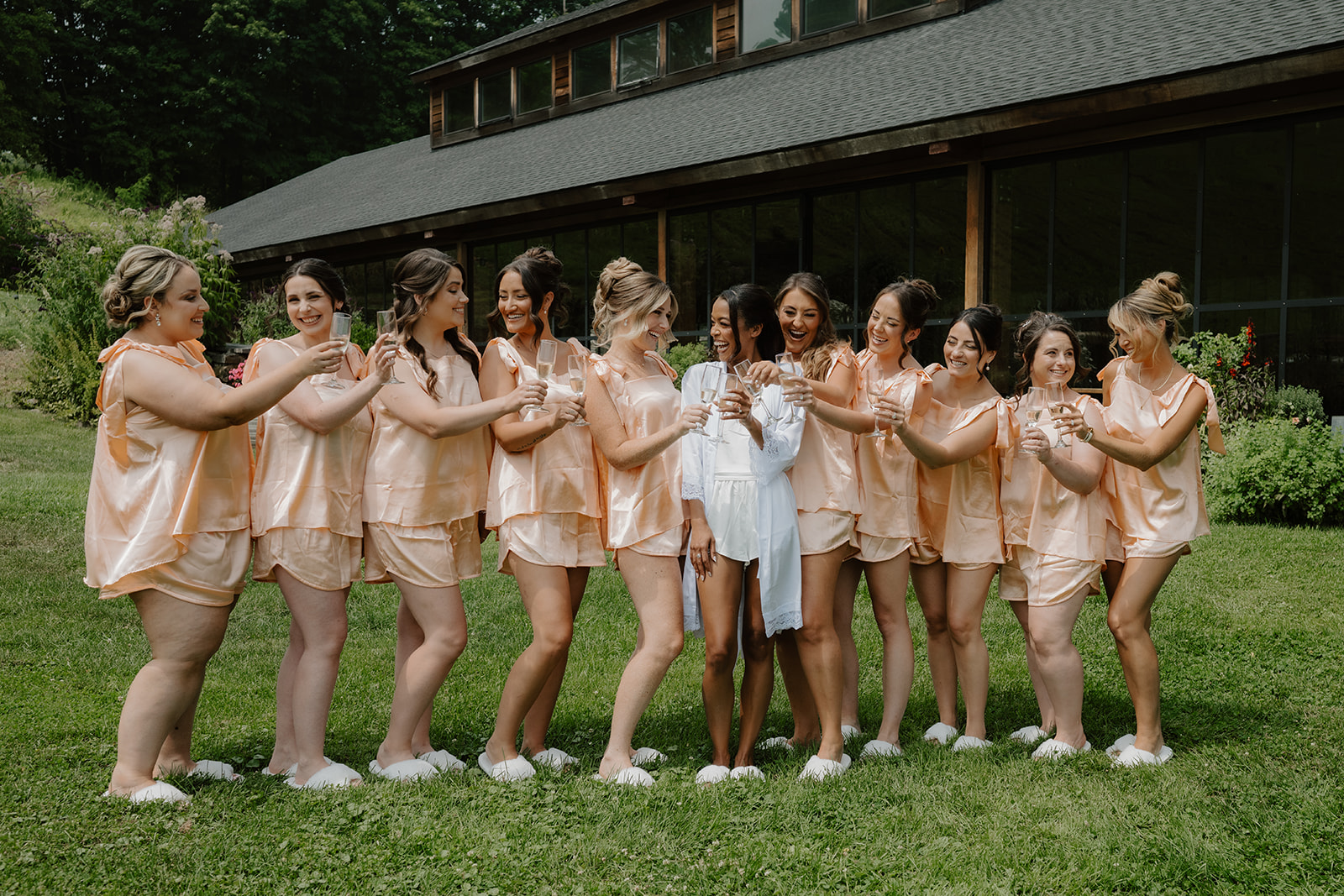 Bride and her bridesmaids line up in matching pajamas on the lawn.