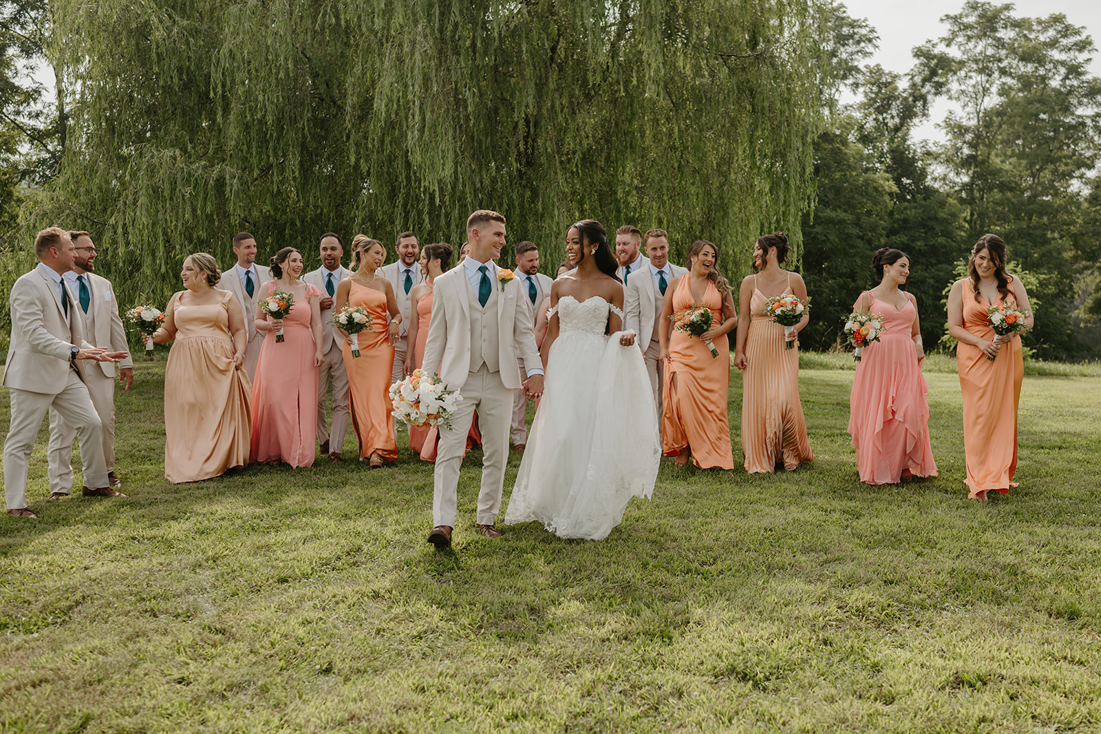 Bride and groom walk toward their bridal party waiting on the hillside.