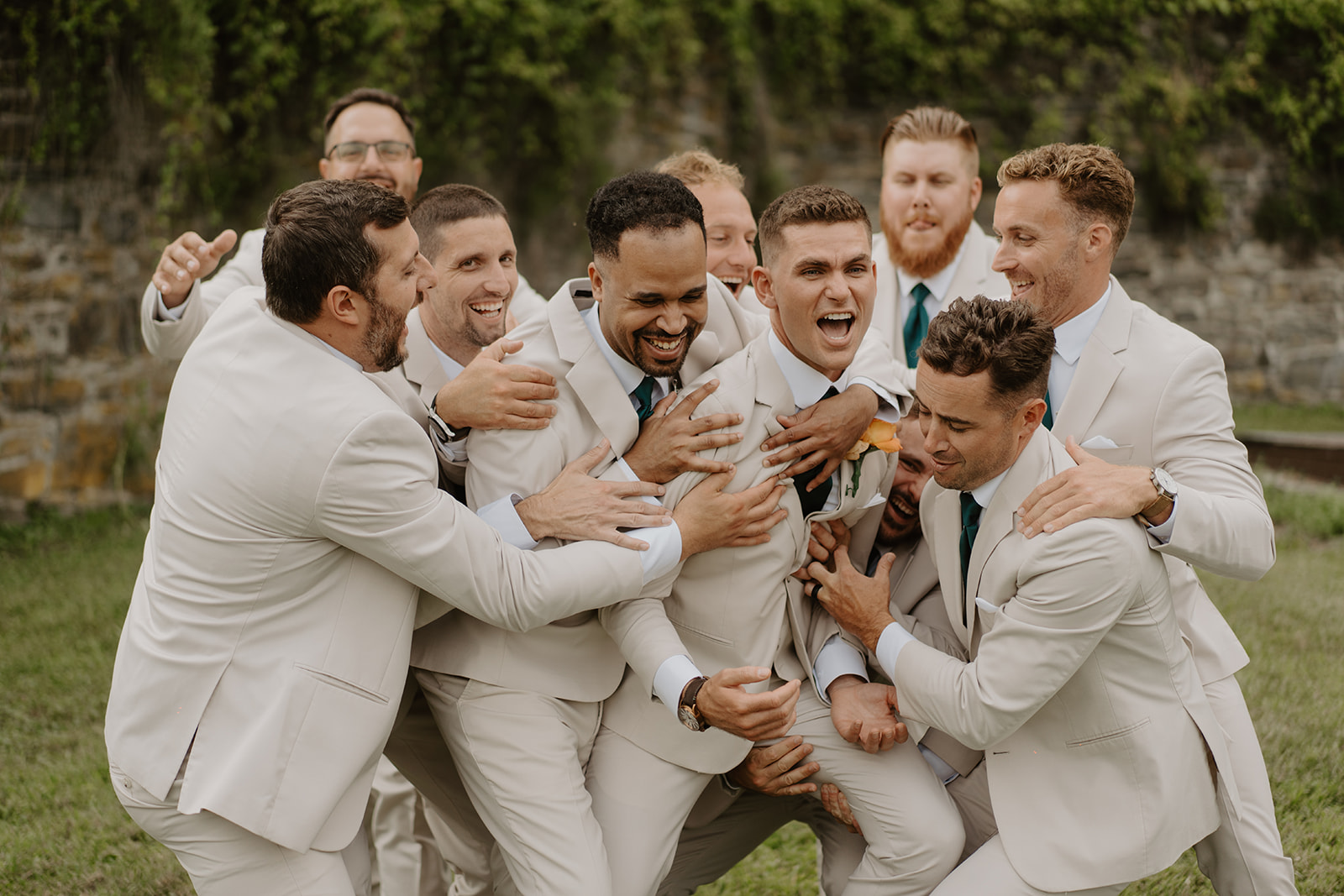 Groomsmen wrestle and laugh together on the lawn before the ceremony.