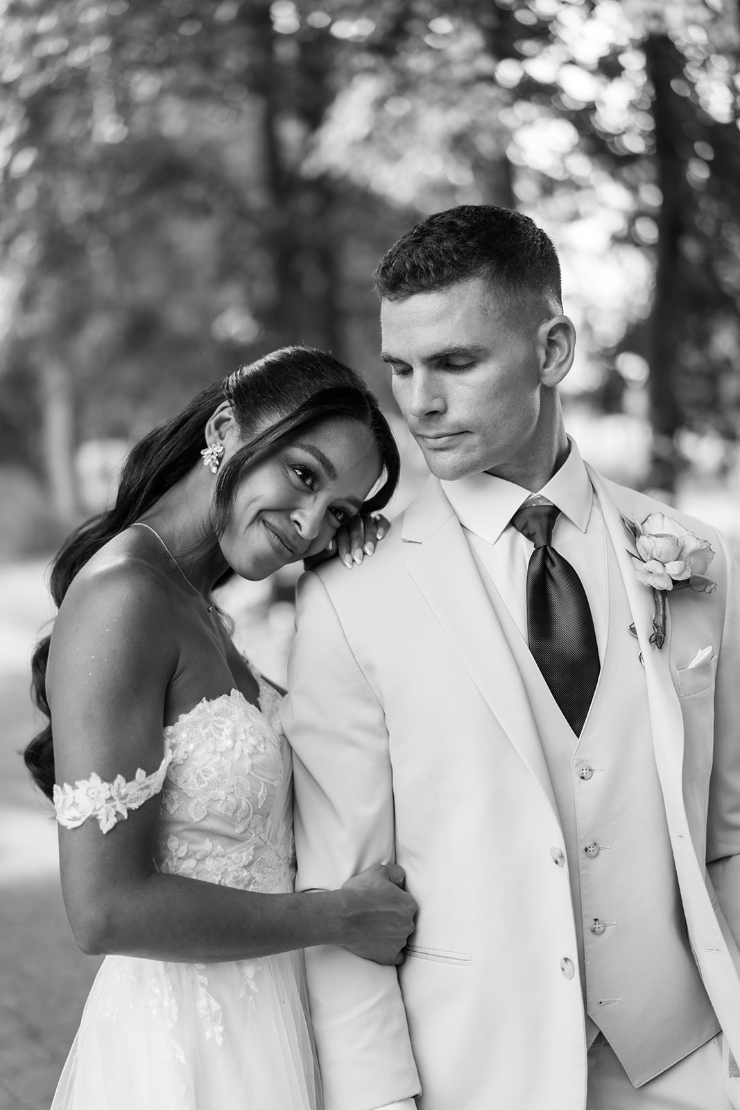 Black and white portrait of the bride resting against the groom's shoulder.