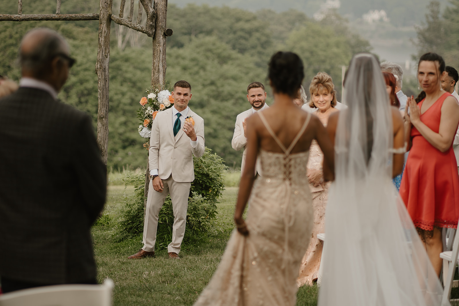 Bride walks toward the ceremony arch as guests turn to watch her arrive.