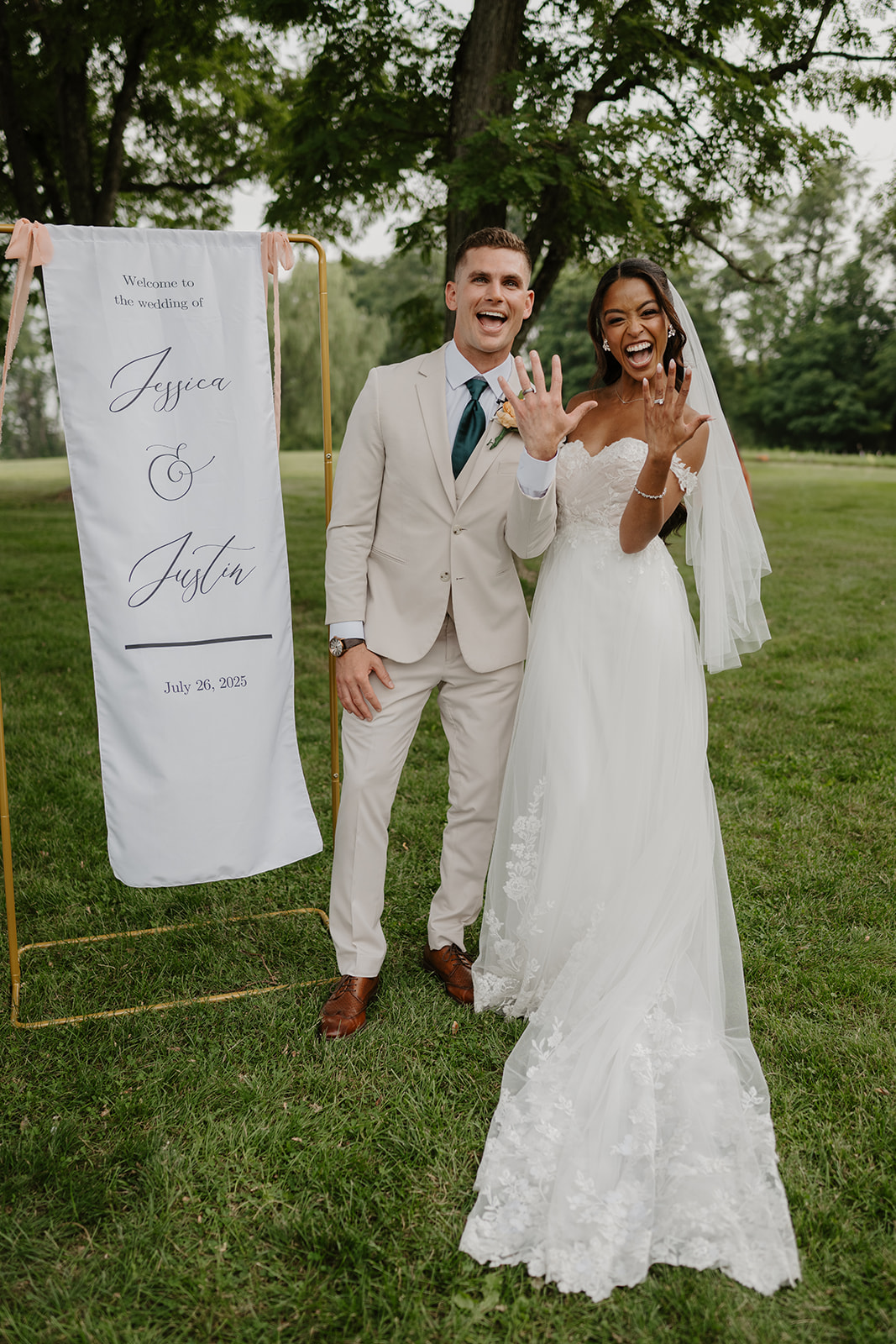 Newlyweds show off their rings beside the welcome sign after the ceremony.