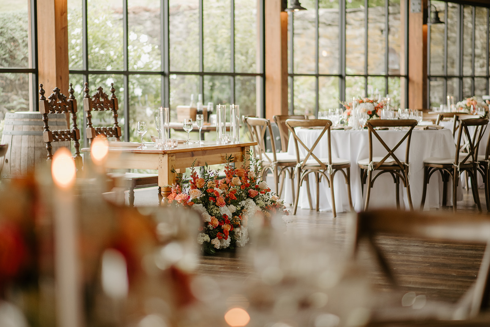 Candlelit reception tables glow against the barn's tall windows at dusk.