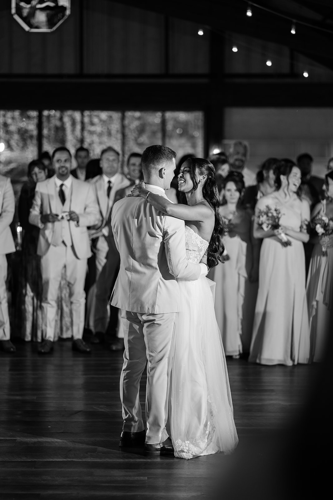 Black and white photo of the couple's first dance surrounded by their guests.