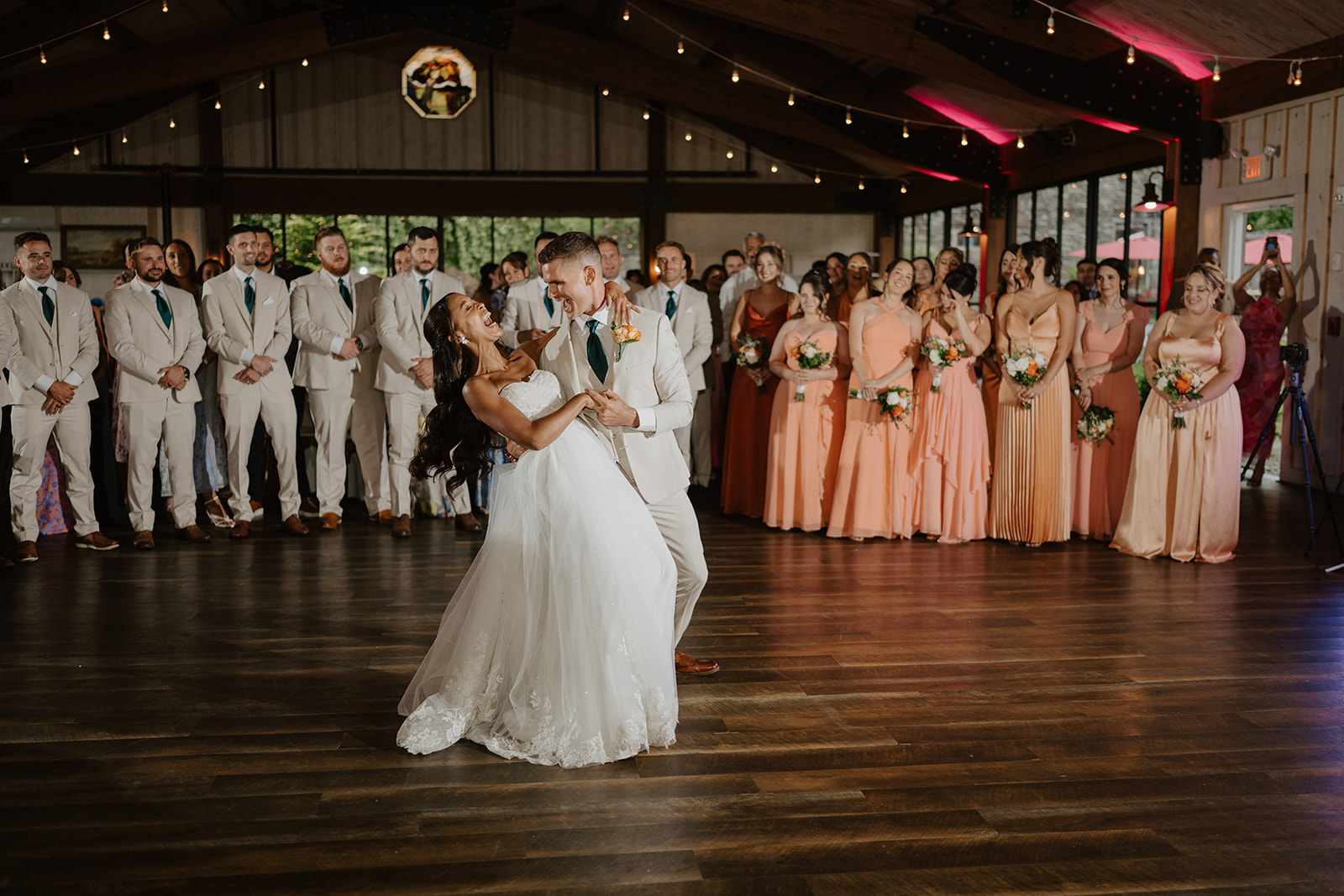 Bride and groom share their first dance as the bridal party watches from the floor.