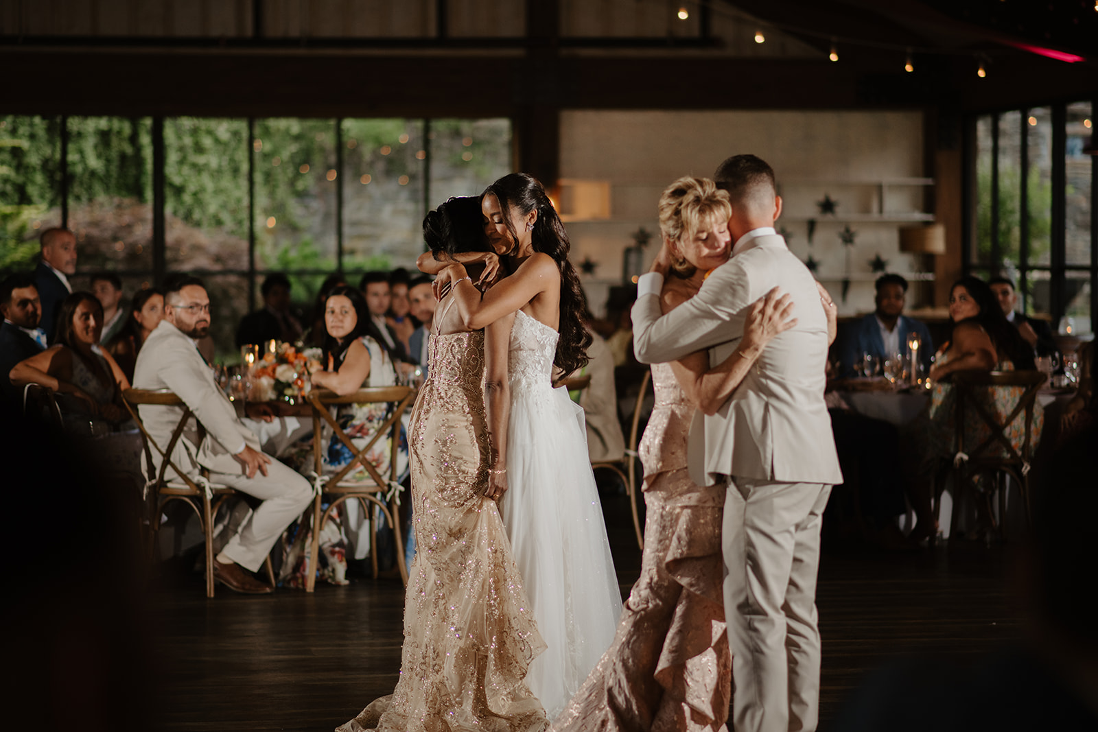 Bride and groom hold each other close during their first dance among the tables.