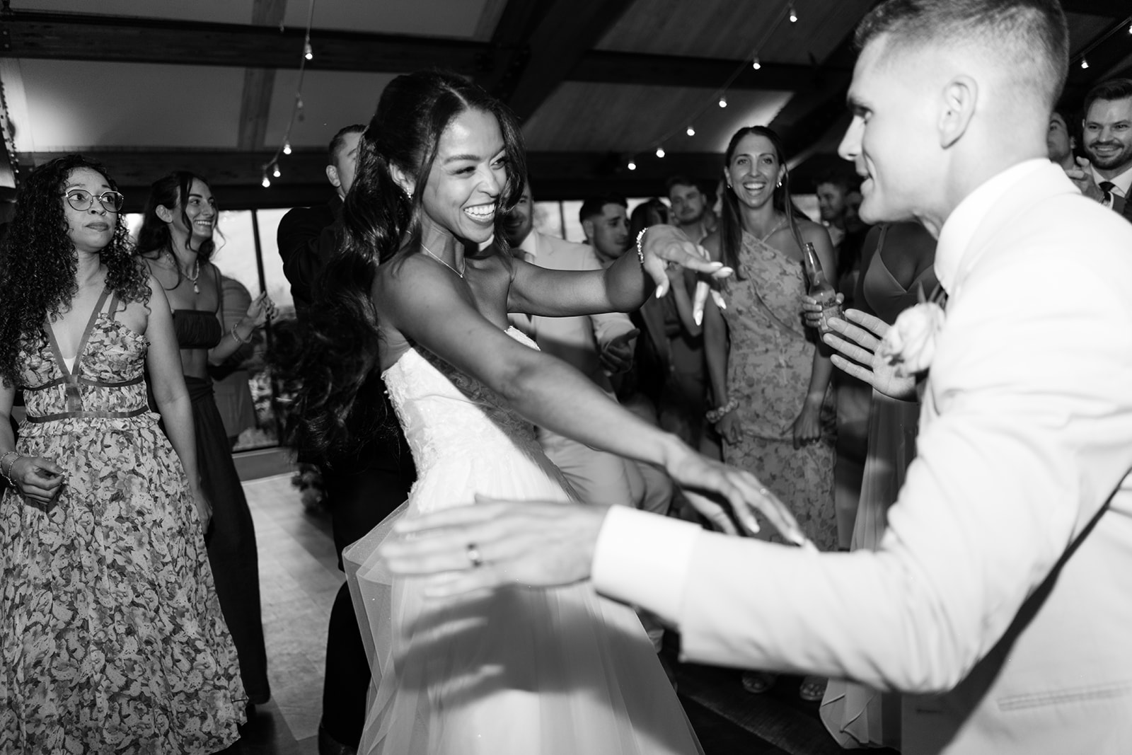 Black and white photo of the bride dancing with the groom in the middle of the party.