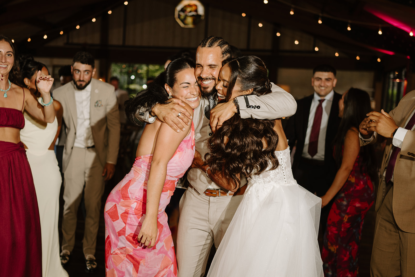 Bride and groom embrace guests on the crowded dance floor.