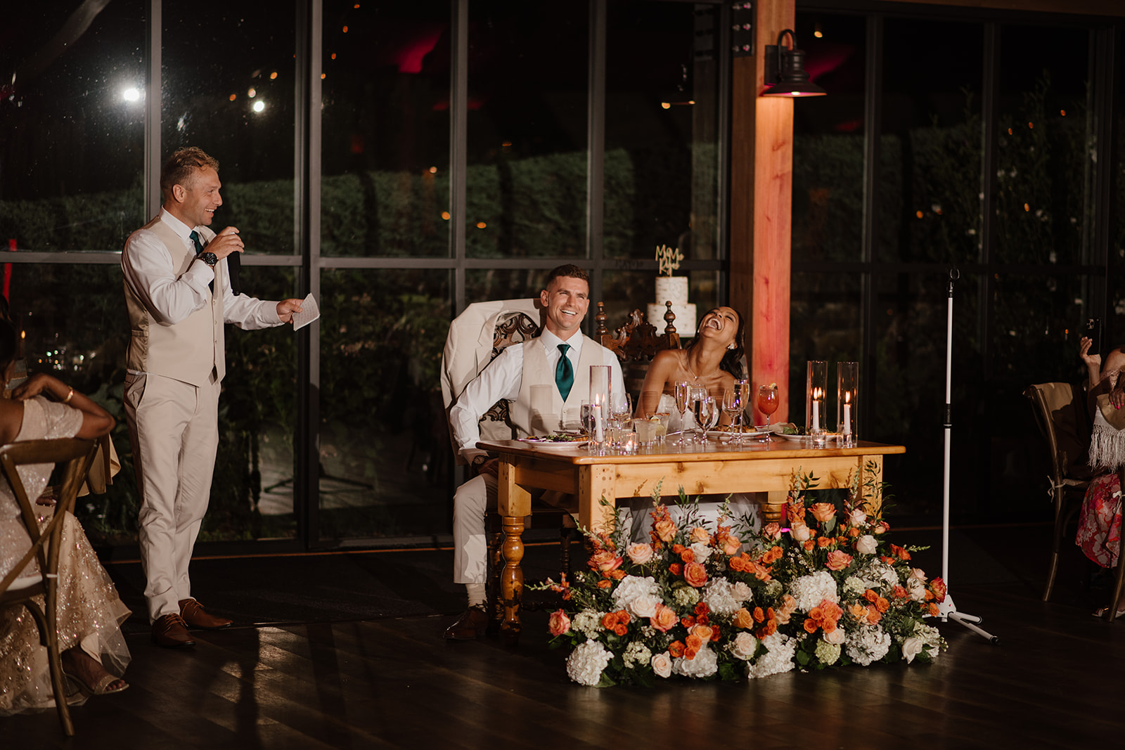 Best man delivers a speech as the couple listens from the sweetheart table.